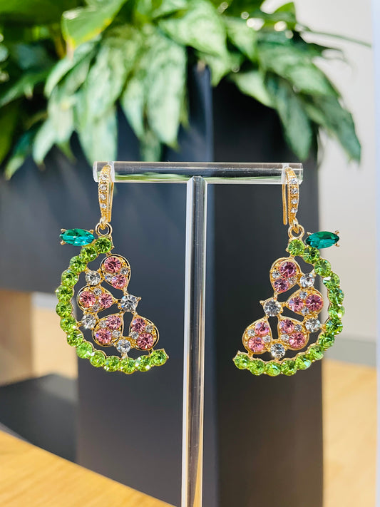 A pair of Gem Watermelon Earrings displayed on a stand, featuring a green and pink gemstone design.